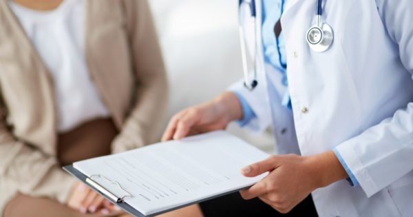 Female doctor holding application form while consulting patient